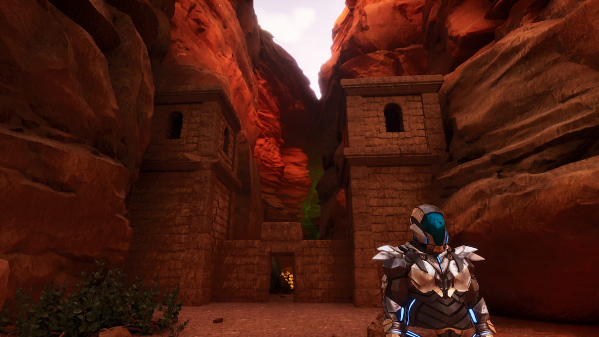 Player in Tek Armor standing in front of the Central Cave entrance in Ark Survival Ascended Scorched Earth