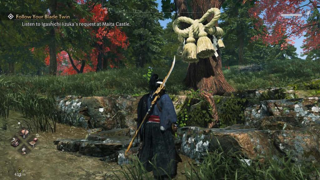A Veiled Edge warrior looking at a tree with a rope ribbon above an underground cave in Rise of the Ronin.