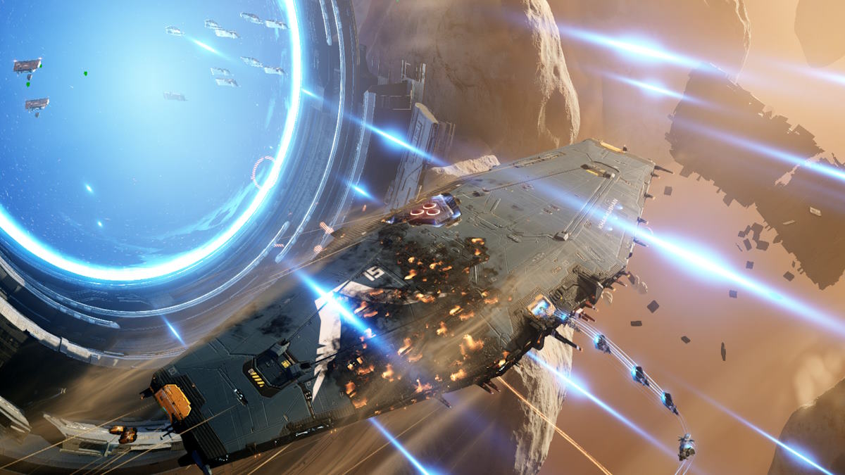 The badly damaged mothership emerges from a hyperspace gate while deploying fighters.